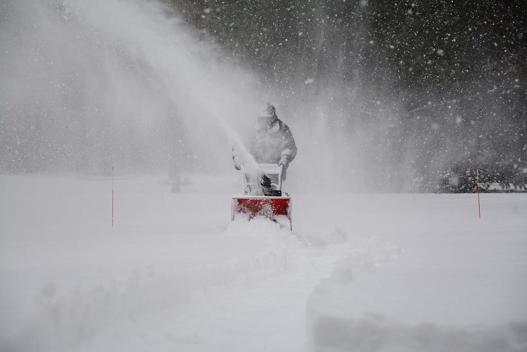 Eine Person räumt Schnee im Winter des Schnee ist überall Schneebeseitigung im Garten