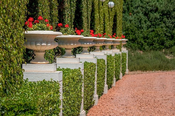 Gartensäulen Beton stehend mit Blumentöpfen und roten Blumen elegant in einem großzügigen Park im Grünen
