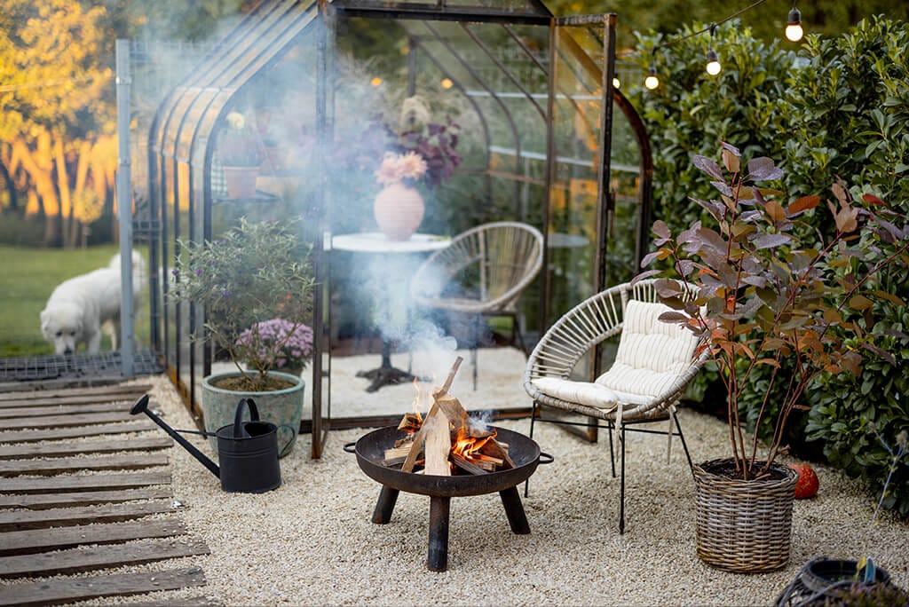 Moderne Feuerstelle im Garten mit erhöhter Feuerschale und Kamin, integriert in eine gepflegte Rasenfläche